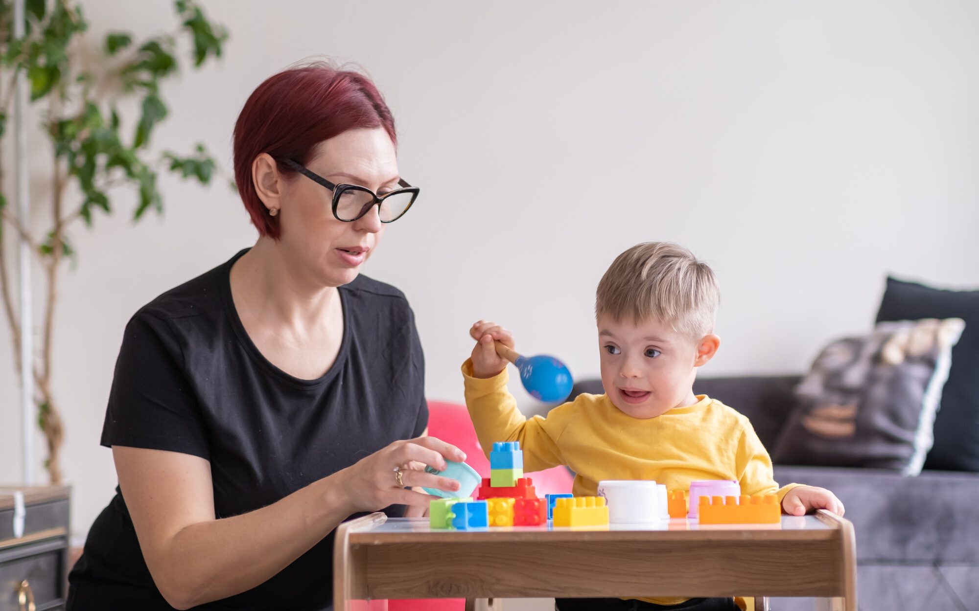 cheerful boy living with down syndrome play games in physical therapy rehabilitation room